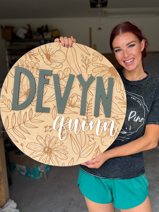 Engraved floral sign on wood with Devyn Quinn being held