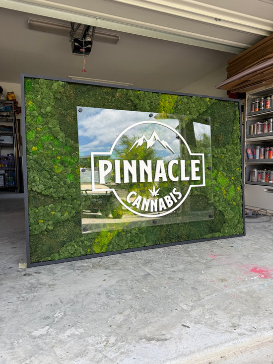 Pinnacle Cannabis Sign with Moss background on display in garage