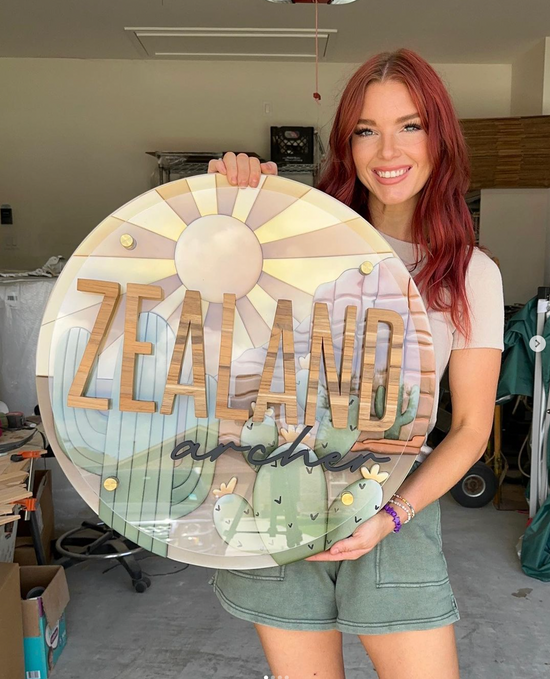 Zealand Archer with desert design on a round wooden sign
